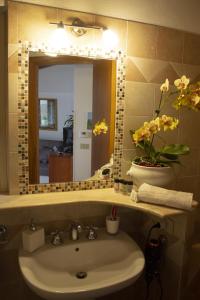 ein Waschbecken mit einem Spiegel und eine Vase mit Blumen in der Unterkunft Casa Marlù in Taormina