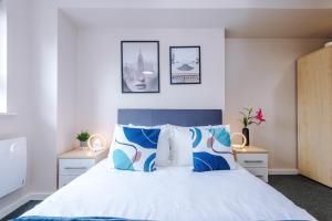 a bedroom with a bed with blue and white pillows at The Belfry - Deluxe 2 Bedroom 2 Bathroom Apartment in Manchester