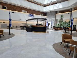 a lobby with tables and chairs and plants at Sea side 87 Sweet Me Eilat אילת in Eilat