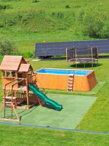 un parque infantil con un tobogán y una piscina en Domki nad potokiem en Muszynka