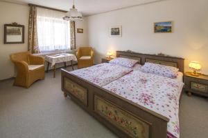 Landhaus Sonnwinkl في فيرتاخ: غرفة نوم بسرير كبير وكرسيين