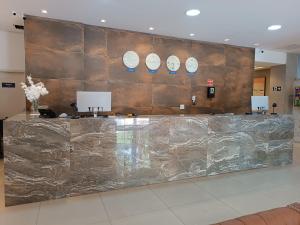 a lobby with a marble counter with plates on a wall at Trip Hotel Ubá in Ubá