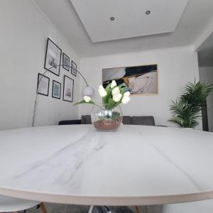 Una mesa blanca con un jarrón de flores. en Dibbio's house, en Guidonia