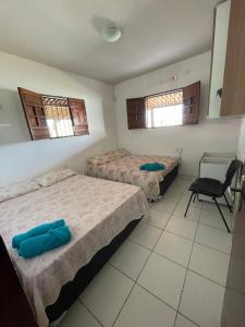 a bedroom with two beds and a chair in it at Kasa Faheina - Praia de Fagundes in Lucena