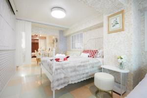 um quarto com uma cama branca e uma mesa em Papillon Paradis Higashi-Shinjuku em Tóquio