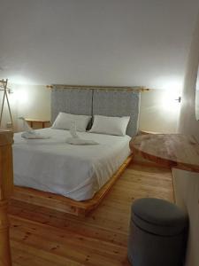 a bedroom with a large bed with white sheets at SMAG Suites in ayios Petros
