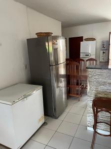 a kitchen with a stainless steel refrigerator and a table at Kasa Faheina - Praia de Fagundes in Lucena
