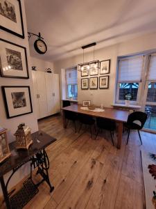 Apartament Czerwone Maki في وارسو: غرفة طعام مع طاولة وكراسي وساعة