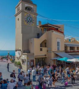 tłum ludzi stojących przed budynkiem z wieżą zegarową w obiekcie Malafemmena Guest House w mieście Capri