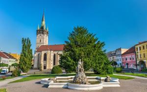 a statue in front of a building with a clock tower at Premium City Centre Bedrooms in Prešov