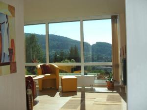 a living room with a large window and a chair at Ferienwohnung Bergblick in Zella-Mehlis