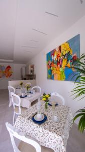 a dining room with white tables and chairs and a painting at Ars de mar in Martinsicuro