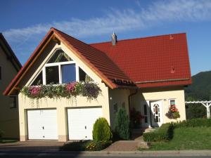 una casa con due porte garage e un tetto rosso di Ferienwohnung Bergblick a Zella-Mehlis