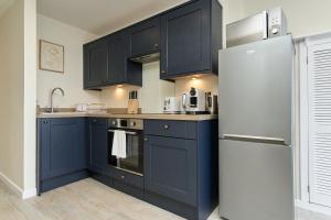 a kitchen with blue cabinets and a refrigerator at West Cowes Penthouse in Cowes