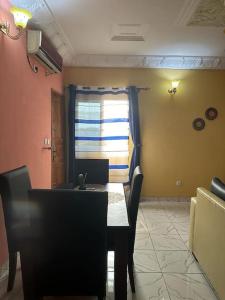 comedor con mesa, sillas y ventana en Appartement meublé Logbessou, en Douala