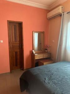 Schlafzimmer mit einem Bett, einer Kommode und einem Spiegel in der Unterkunft Appartement meublé Logbessou in Douala
