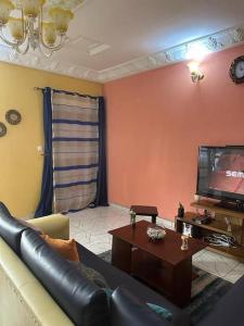 a living room with a couch and a tv at Appartement meublé Logbessou in Douala