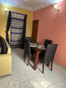 una sala da pranzo con tavolo, sedie e divano di Appartement meublé Logbessou a Douala