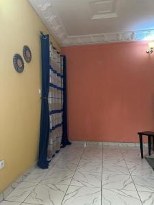 a room with a wall with a curtain and a clock at Appartement meublé Logbessou in Douala