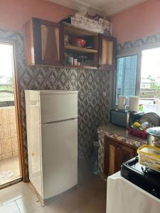 eine Küche mit einem weißen Kühlschrank im Zimmer in der Unterkunft Appartement meublé Logbessou in Douala