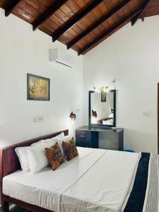 a bedroom with a large white bed and a mirror at Villa Roy Bentota in Bentota