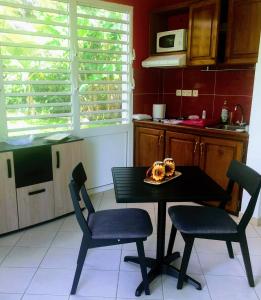a kitchen with a table and chairs with a plate of food at l'HABITATION in Le Gosier