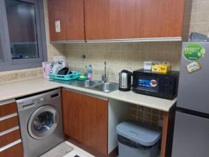 uma cozinha com um lavatório e uma máquina de lavar roupa em Top House Hostel em Abu Dhabi