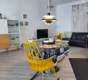uma sala de estar com uma mesa e cadeiras amarelas em Arctic Apartment with own Sauna em Rovaniemi