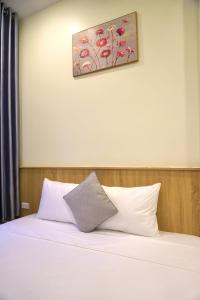 1 cama con almohadas blancas y una pintura en la pared en Phúc Đức Hotel, en Thanh Hóa