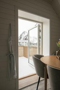 una puerta abierta a una terraza con mesa y sillas en Koselig toppleilighet med fantastisk utsikt en Svolvær