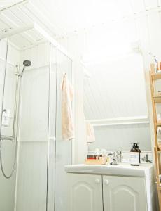 a white bathroom with a shower and a sink at Koselig toppleilighet med fantastisk utsikt in Svolvær