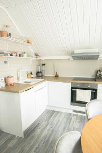 una cocina con armarios blancos y una mesa con sillas. en Koselig toppleilighet med fantastisk utsikt en Svolvær