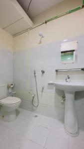 a white bathroom with a toilet and a sink at Hotel Jom Jom International in Dhaka