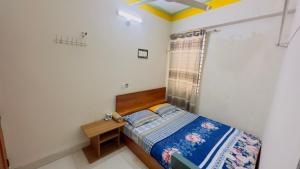 a small bedroom with a bed and a table at Hotel Jom Jom International in Dhaka
