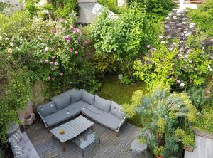 einen Blick über einen Garten mit Sofa und Blumen in der Unterkunft Peaceful green setting near to Paris Center in Pantin