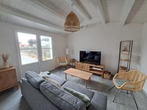 ein Wohnzimmer mit einem Sofa und einem TV in der Unterkunft Echapee familiale a l Epine in LʼÉpine