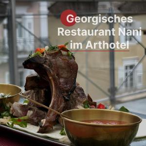 une plaque de nourriture avec un morceau de viande et deux bols dans l'établissement ART HOTEL HOUSE ONE, à Baden-Baden