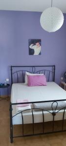 a bedroom with a bed with a purple wall at Giannis Stella apartment in Mourteri