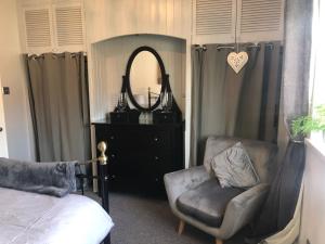 a bedroom with a bed and a chair and a mirror at Fabulous flat in the fantastic location of Gosforth in Gosforth