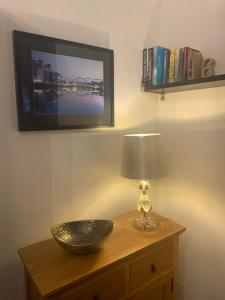 a table with a lamp and a television on a wall at Fabulous flat in the fantastic location of Gosforth in Gosforth