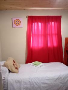 1 dormitorio con cortina roja y cama blanca en Cabaña La Solanita en Termas de Río Hondo