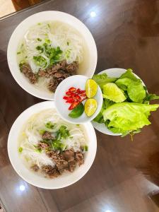 tres platos de comida con fideos y ensalada en una mesa en TAM COC HARBOR VIEW HOTEL, en Ninh Binh