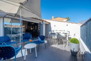 patio z krzesłami, stołami i parasolem w obiekcie Maison moderne avec piscine et tennis w Saint-Tropez
