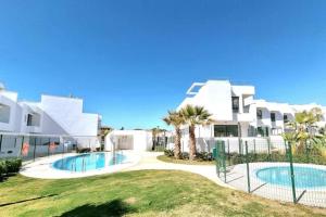 a large white building with a swimming pool and palm trees at Modern terrassed house close beach in Málaga