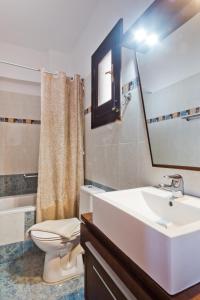 uma casa de banho com um lavatório, um WC e um espelho. em Arkasa Bay Hotel em Arkasa