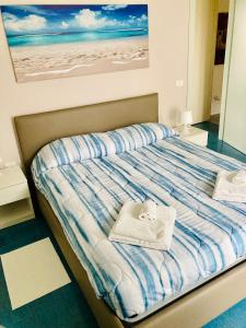 a bed with a towel and a picture of the beach at Appartamenti Pesaro Mare Ledimar in Pesaro