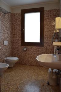 a bathroom with two sinks and a toilet and a window at Colombara Farmhouse in Mestrino