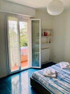 een slaapkamer met een bed en een glazen schuifdeur bij Appartamenti Pesaro Mare Ledimar in Pesaro