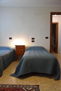 a bedroom with two beds and a wooden dresser and a bedskirts at Colombara Farmhouse in Mestrino