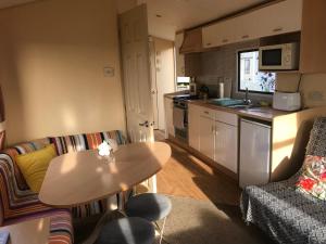 a small living room with a table and a kitchen at Ocean Edge Holiday Home in Heysham